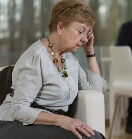 A woman sits with a thoughtful expression.