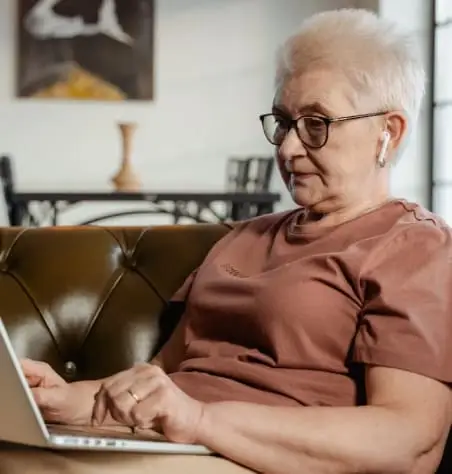 Senior woman using a laptop on a couch.