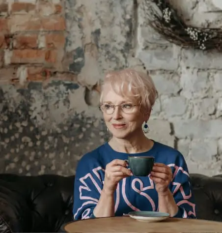 Woman with gray hair holding a cup of tea.