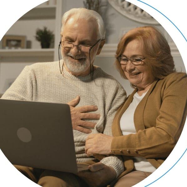 Senior couple smiling while using laptop.